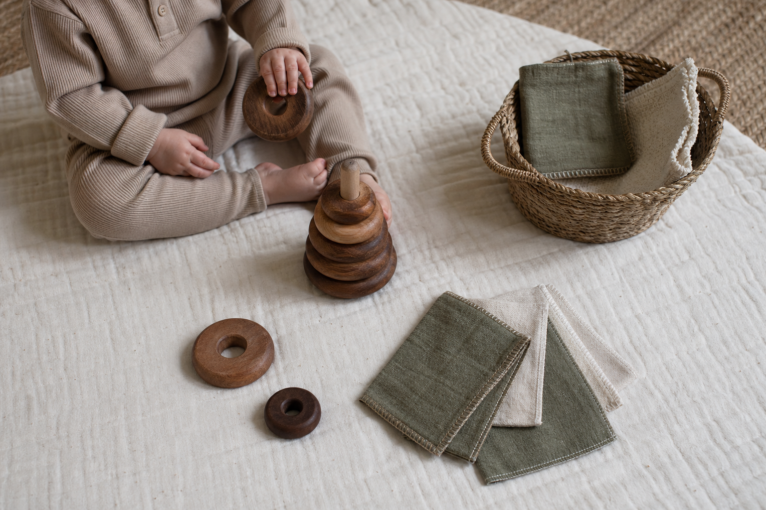 Wooden baby toys and soft fabric pieces arranged on a natural cotton play mat
